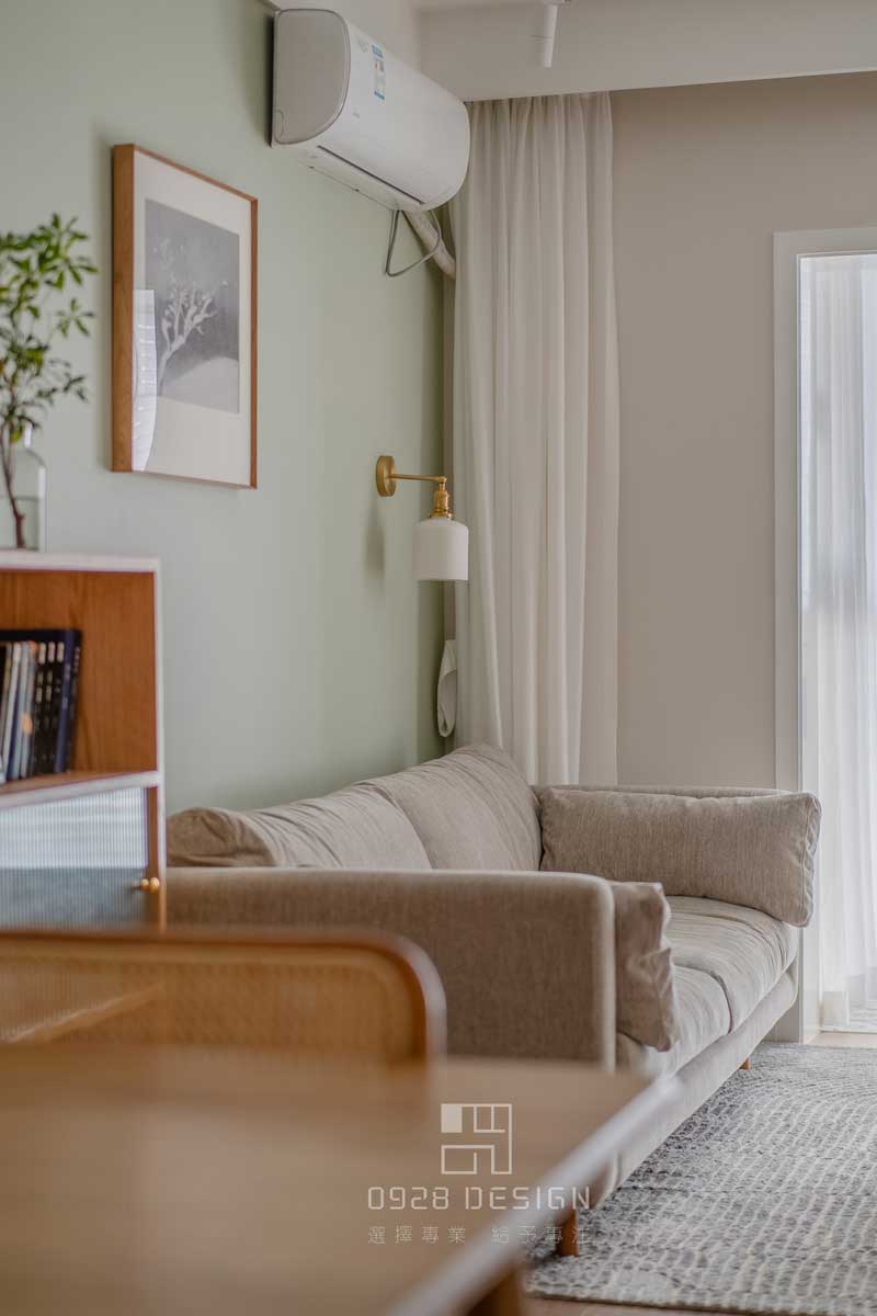 沙發背景灰綠色的墻面，增加了一點俏皮感，在沙發背景掛畫的選擇上沒有用常規的形式，單一幅正方形的雪景圖，加深了深遠悠長的感受。壁燈選擇瓷器的燈罩和金色的吊桿，點綴精致感又帶有復古的意味，和餐廳吊燈是一套購買。