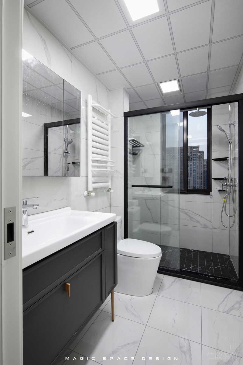 白色的大理石磚面讓采光受限的主衛空間緩解了尷尬，布局中實用與時尚并舉，基礎的干濕分離，黑色邊框的淋浴拉門，搭配上深黑的防滑地磚，除了滿滿的肌理感也有區分的作用。